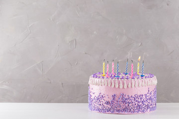 Pink birthday cake with colorful blown out candles