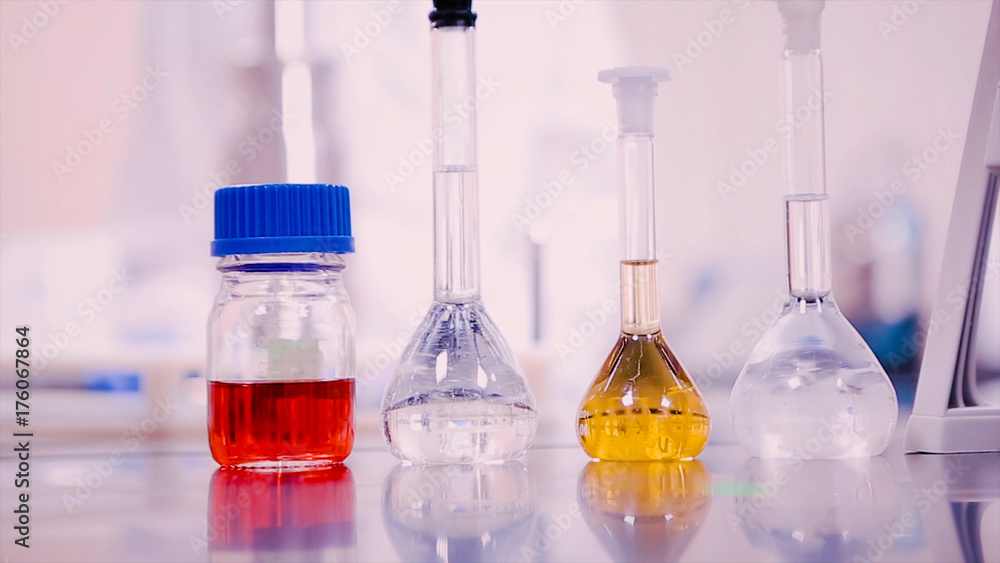 Aufkleber laboratory flasks and beakers with liquids of different colors on lab table