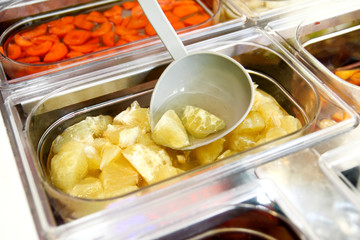 Set of fruit dessert for make a smoothie. Fresh fruits juices. The woman's hand making smoothie fruit, takes with ladle the fruit juice from the water and the fruit into a plastic cup. Healthy foods.