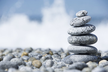 Stones pyramid on pebble beach symbolizing stability, zen, harmony, balance, concept with blur sea background