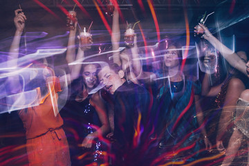 Happy company on dance floor. Joyful New Year in night club, active Christmas celebration in motion. Disco party in blurred colors, modern youth life, pickup concept - obrazy, fototapety, plakaty