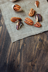 Pecan nuts on piece of cloth over wooden table.