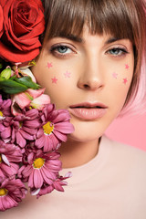 woman with stars on face posing with flowers