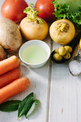 Vegetables, olives and spices over white wooden table.