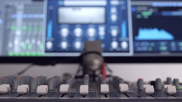 Tweaking a digital mixing board in front of a computer.