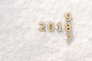 Wooden numbers forming the number 2018 on white snow sparkling in the sun backgraund texture