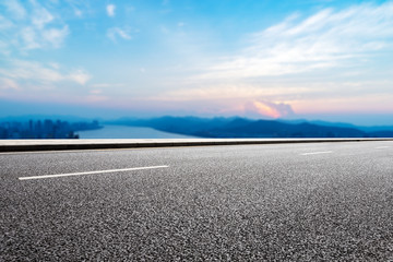 empty asphalt road with modern city near long river
