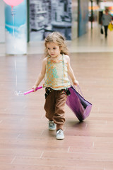 Little kid girl walking on a mall with shopping bag.