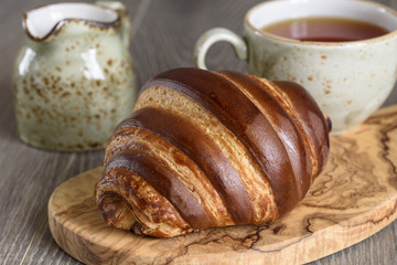 Fresh croissants and tea cup for breakfast on wooden vintage table