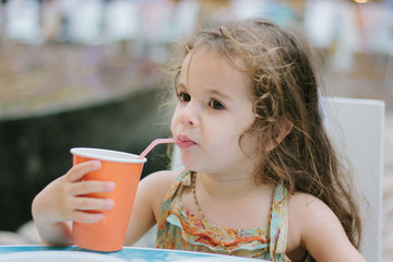 Little kid drinks cola at the cafe or restaurant