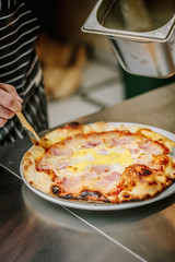 Chef smears olive oil to the top of pizza.