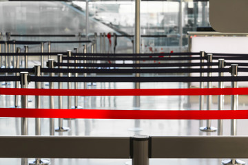 Blocking barriers, airport interior, red stop line, selective focus.