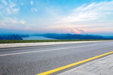 empty asphalt road with modern city near long river