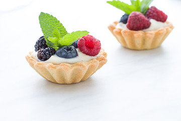 Mini tarts on the plate close up. Homemade dessert with delicious catalonian traditional cream and fresh berries
