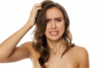 Obraz premium Beautiful young woman has an itch in her hair on white background