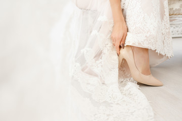 The bride is wearing wedding shoes, in a wedding dress.