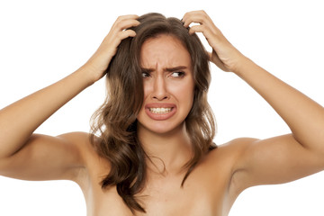 Fototapeta premium Beautiful young woman has an itch in her hair on white background