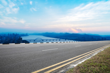 empty asphalt road with modern city near long river