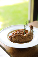 Coq au vin, chicken stewed in red wine with carrots and potatoes on wood background , France food