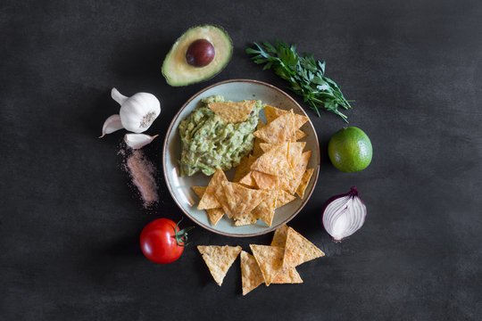 Plate of guacamole with tortilla chips and ingredients