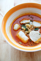 Fish and fishball Tom yum noodle on wood background , Thai food