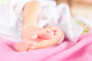 Fototapeta na wymiar Soft newborn baby feet against a pink blanket.