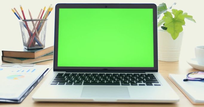 Laptop on desk with green screen.