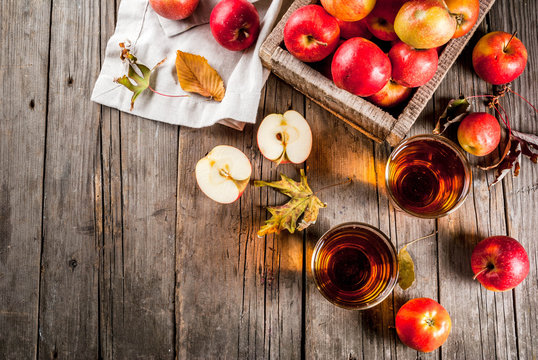 Fresh organic farm apple juice in glasses with raw whole and sliced red apples, on old rustic wooden table, copy space top view