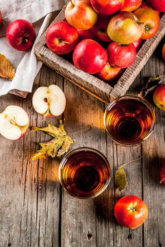 Fresh organic farm apple juice in glasses with raw whole and sliced red apples, on old rustic wooden table, copy space top view