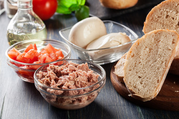 Ingredients ready for preparing bruschetta with tuna, mozzarella cheese and tomatoes