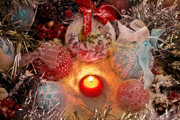 Fototapeta na wymiar Christmas candle in the snow surrounded by Christmas toys and balls