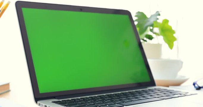 Laptop on desk with green screen.