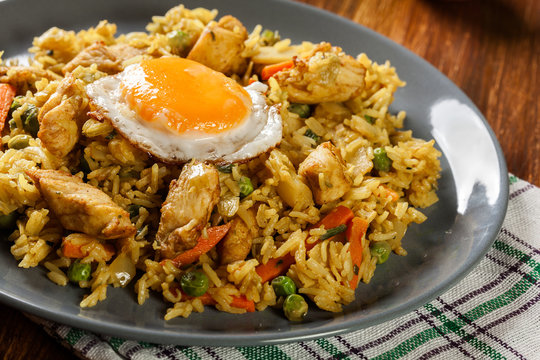 Fried rice nasi goreng with chicken egg and vegetables on a plate.
