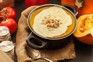 Pumpkin soup with cream and croutons in a pot