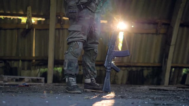 Low section of soldier with rifle standing indoors