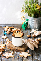 Homemade shortbread star shape sugar cookies different size in vintage mug and as garland on old wooden table decorated by Christmas tree and gifts. Christmas mood theme.