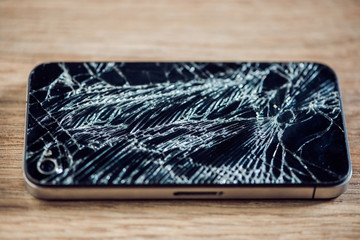Smartphone display with broken glass on a wodden table