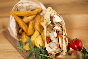 Burrito with grilled chicken and vegetables. Shawarma from juicy beef, lettuce, tomatoes, cucumbers, paprika and onion in pita bread.