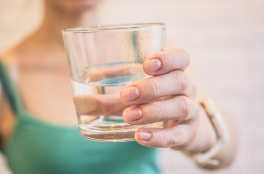 Glass with pure water in a female hand close-up