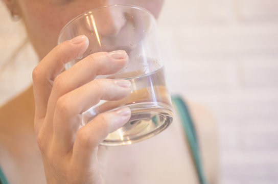A young woman drinks pure water from a glass