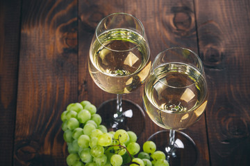 Beautiful White wine in wine glass with a bunch of green grapes, on a wooden background with free space - obrazy, fototapety, plakaty