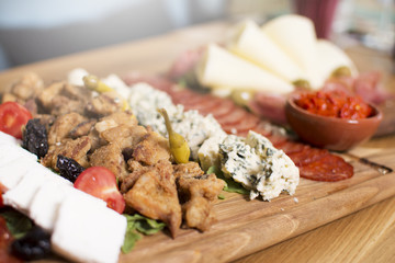 Mediterranean olives, sun-dried tomatoes, baguette slices, camembert cheese and spices on wooden background. Sausage and prosciutto slices on a wooden board. Appetizers served at an event.