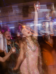 Happy New Year party in blurred motion. Joyful lady at Christmas discotheque, modern youth life,...