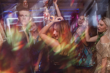Dancing at night club in blurred motion. Joyful friends at Christmas discotheque, active New Year...