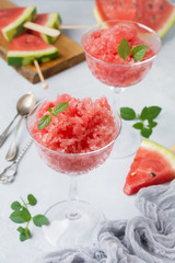 Watermelon granite with mint, summer refreshing drink in glass on a gray concrete background. Selective focus.