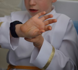 Chłopiec ubrany w garnitur do Pierwszej Komunii ogląda zegarek smartwatch, który dostał w prezencie