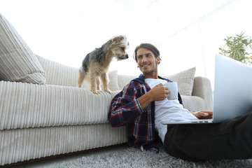 handsome guy is drinking tea sitting on the floor near the couch