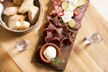 Mediterranean olives, sun-dried tomatoes, baguette slices, camembert cheese and spices on wooden background. Sausage and prosciutto slices on a wooden board. Appetizers served at an event.
