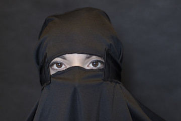 Portrait of woman in burqa against black background