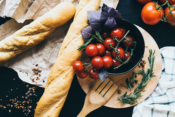 Tasty fresh tomatoes in a stylis black dish with delicious bread lying on wooden cutting board...